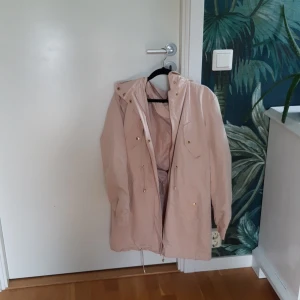 BIKBOK - En rosa vind/regn jacka, perfekt för hösten. Ganska långt ner på benen men väldigt bekväm, dragkedja och knappar.