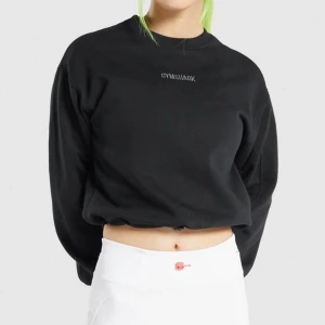 Gymshark svart sweatshirt - Croppad sweatshirt som är perfekt till uppvärmningen eller träning ute i kallare väder. Mjukt fleecefoder inuti, broderad logga fram och dragsko vid midjan. Bra skick. Skriv vid funderingar! 