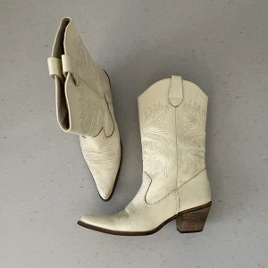 Vintage Cowboy Boots i vitt läder - Vintage Cowboy Boots i vitt läder. Förmodligen äkta läder men vet inte säkert. I använt skick: lite av lädret är avskalat på ena skon - se sista bilden. Annars väldigt fina! Storlek 40 men skulle även kunna passa en 39a! Klacken är 5-6cm hög. 