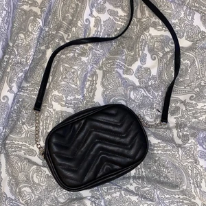 Väska - En svart helt oanvänd axelremsväska.