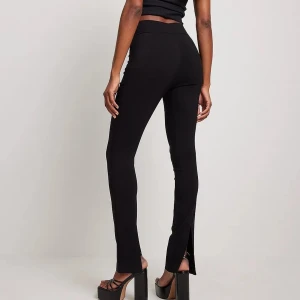 Oanvända svarta byxor med slits  - Säljer dessa fina leggings/byxor från NA-KD i storlek XS/S. Säljes för att jag har två! Sitter som en smäck! 
