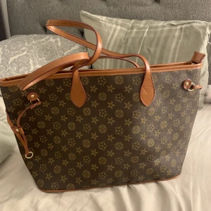 Brun väska - En stor brun väska. Aldrig använd. Har ett till fack på baksidan och tre mindre fack inne i väskan. Man får plats med mycket i den. 