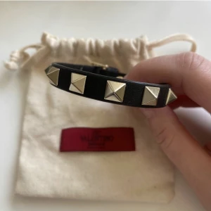 Valentino armband - Svart valentino armband med guldiga nitar. Armbandet är i jätte bra skick och kanppt använt. Box och påse medföljer dock är boxen en aning skadad men den följer med om man vill de.