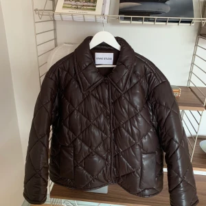 Stand Studio pufferjacka - Quiltad pufferjacka i mörkbrunt konstskinn från Stand Studio. Storlek 36 men den är oversize i storleken passar 36-40. Den är lite använd så typ i nyskick :) Nypris 3900kr