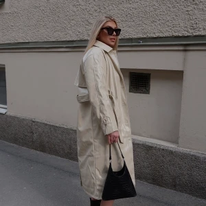 Ljus läder trenchcoat - Ursnygg trenchcoat från Gina Tricot som har en cremevit färg och är i lackad läder (fejk såklart)  Använd två gånger. Gott som ny. Perfekt till alla årstider. Nypris: 899kr 