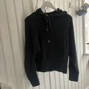 Mysig stickad hoodie. Jättefin men tyvärr lite liten för mig. Strl XS. Mörkgrå, lätt melerad. Knyte vid halsen med silvrig detalj. Bra alternativ till dyrare cashmere hoodies. 