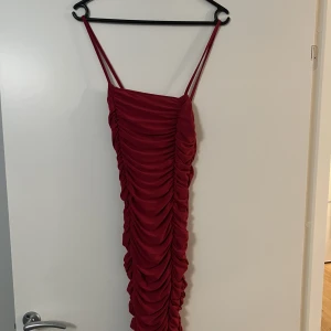 Röd miniklänning oanvänd  - Helt ny oanvänd röd midiklänning med rynkigt tyg. Över knäna 