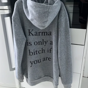 Grå hoodie med text på ryggen - En grå hoodie i bra skick som det står”karma is only a bitch of you are
