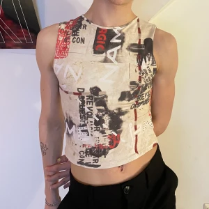 Y2k 2000s babytee linne beige röd grå - Beiget linne med babytee fit med vitt, rött och grått graffiti liknande mönster 🎞 Så snygg till ett par stora byxor och dadsneakers för dne ultimata 2000s looken!