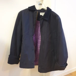 Vårjacka Weekday - En så himla fin vårjacka, mörkblå med lila foder. Från Weekdays herravdelning men passar som unisex enligt mig. Den är i väldigt gott skick och knappt använd då jag har för många jackor. Krage i manchester. Knappar & dragkedja. Massa bra fickor ut&insida.