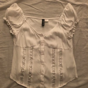 Vit blus  - Säljer denna super söta blusen från H&M i storlek 38/M men passar även de som har 36/S. Bara använd fåtal gånger men säljer pågrund av att den är för liten💕