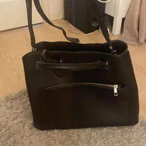 Svart väska  - En jättefin svart väska som är hur rymlig som helst! Det är ett fack med dragkedja i mitten sedan två tack som stängs med knapp på sidorna om dragkedjan i mitten! Inga fel på väskan alls den har bara legat.. 