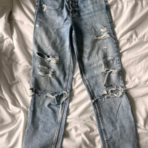 Slitna momjeans strl 32 - Momjeans strl 32 från H&M. Går till ankeln på mig som är 170cm. Ljus denimblå, slitningar. Säljes pga för små för mig! 