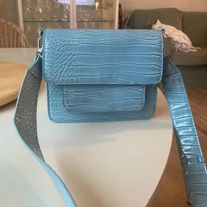 Blå krokodilmönstrad väska  - Fina väska som nästan aldrig blivit använd då jag har alldeles för många väksor. Rymmer mycket men känns inte för stor. 