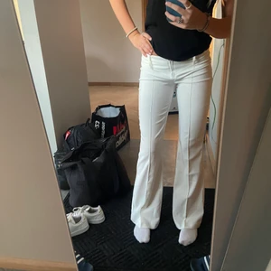 Vita kostymbyxor low waist  - Lågmidjade vita kostymbyxor från vero Moda i storlek 34. Säljs inte längre och långa i modellen. Passar på mig som är 173cm. Inget täcken på användning.