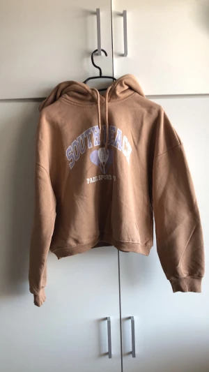 Brun/beige hoodie - Fin hoodie med ett jätte fint tryck! Köptes för 150 kr. Passar till stockholmsstilen och till andra stilar.