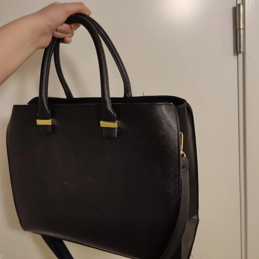 Stor svart väska med handtag eller axelrem. Guld detaljer. Rymmer allt från träningskläder till datorer. Den är använd men väldigt fint skick. . Väskor.