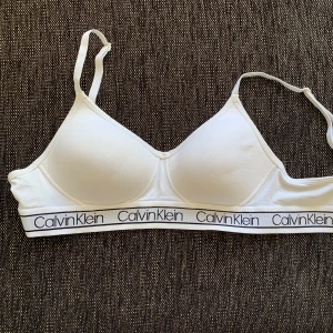 Calvin Klein BH - Nu säljer jag min vita Calvin Klein BH med svart text i storlek M. Den är i nyskick med knäppning bak, alltså inte den ”traditionella” Calvin toppen🤍