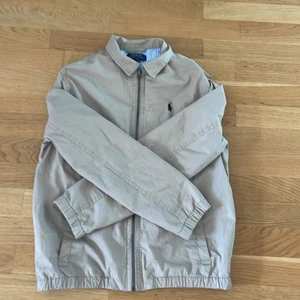 Polo raulph lauren jacka  - En beige polo raulph lauren jacka köpt på kidsbrandstore 2021 i oktober tänkte köpa den som sommarovershirt så använde den inte förens nu i sommar då jag upptäckte att den vart för liten 