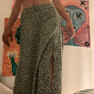 Medellång blommig kjol  - Medleång, somrig grön blommig kjol ifrån H&M. Storlek 40. Använd fåtal gånger. Har två slittar på varje sida. Dragkedja på ena sidan.