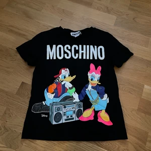 Moschino - Säljer en dam HM&Moschino tshirt i storlek XS. Detta är en kollaboration mellan HM och Moschino. Köpt för 600kr, använd 2 gånger sedan dess har den bara legat i tjejens garderob.