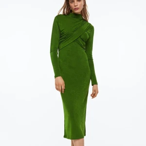 H&M omlottklänning  - En lång, figurnära klänning i trikå med hög krage. Klänningen är omlottlagt fram med en draperas effekt. Lätt nedhasad axel och lång ärm. Rakt skuren nedtill.  Skick som ny, använt bara två gånger. Inga defekter. Köpte för 399:-