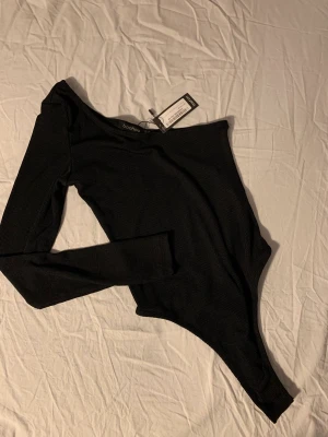 Svart oneshoulder body - Svart, ribbad oneshoulder-body. Aldrig använd med prislappen kvar! Storlek M men passar S. 👠