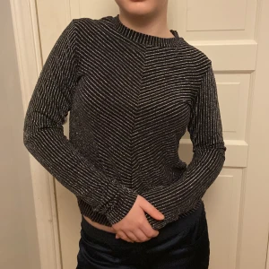 Svart långärmad topp  - Jag har storlek S , men eftersom den är så stretchig så kan en som har M också ha den. Jag använder inte denna topp det är därför jag säljer den men jag tycker fortfarande den är perfekt till en fest. Långst ner på tröjan i mitten finns det en detalj.