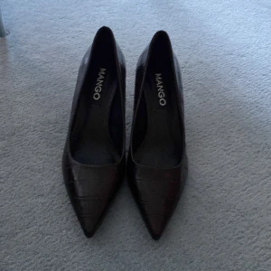 Mango pumps - Oanvända pumps från Mango. Liten repa som knappt är synbar. Färgen är mörkt vinröd åt det bruna hållet.  Storlek 38