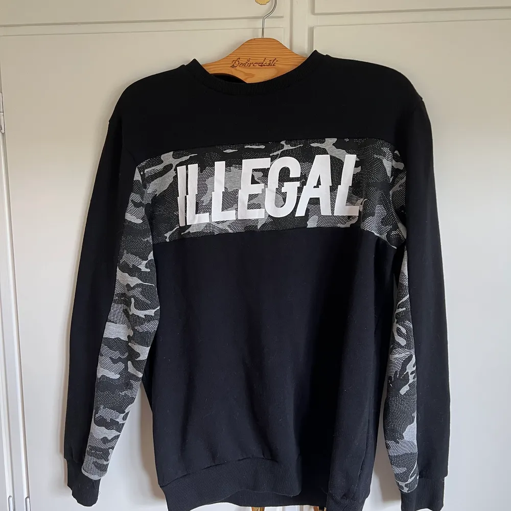 Sweatshirt av märket House köpt i Polen. Använd 2-3 gånger. Tryck där det står Illegal och deltaljer i grå kamouflage. Storlek XL. Tröjor & Koftor.