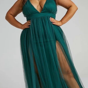 Lång mörkgrön balklänning med slits - Endast prova balklänning med slits och korsad rygg. Mörkgrön/ emerald grön. Tyckte tyvärr inte om hur den satt på mig men väldigt fin färg och form. Bilder från hemsidan. Pga dyr tax och retur pris kunde jag inte skicka tillbaka så jag hoppas att den passar dig och är din dröm klänning! Köptes för 800kr och är i nyskick oanvänd.