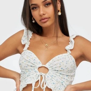 Blommig topp - Säljer denna supersöta blommiga toppen som är perfekt nu till sommaren. Toppen köptes på Nelly för ca 2 år sedan och är endast använd någon enstaka gång.