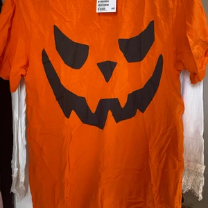 Halloween  - En orange T-shirt med pumpa ansikte. Passsr bra till halloween. Storbild storleken. 