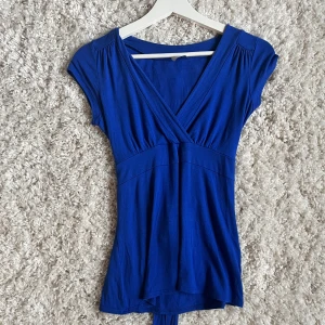 Blå topp - En v-ringad topp med ett snöre som görs till en knut/rosett, den är i en fin blå färg. Jag köpte den secondhand. Vet inte riktigt vilken storlek den är i men jag skulle säga S/M Säljer den för 75kr +frakt.