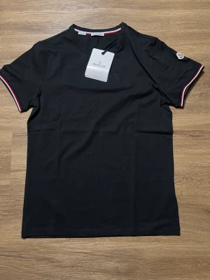 Moncler T-shirt - Moncler T-shirt Förg: svart Storlek: M Märke: Moncler  Säljer min moncler T-shirt, den är använd bara några få gånger 2-3 ggr. Är i nyskick. Jag har köpt den från en vänn som jag litar på. Jag har inte kvittot.   Tveka inte att kontakta mig!