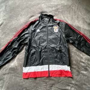Benfica windbreaker - Vintage Benfica vindjacka. Köpt secondhand helt oanvänd. Sitter löst längst ner, kan säkert sys en söm.