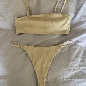 Bikini  - Bikini med bandeu top och trosor i stringmodell. Trosorna går högt upp på höftbenen, toppen går det att ta av banden på. Passar S-M 