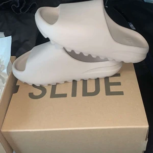 Yeezy Slides - Säljer min pojkväns helt nya och oanvända yeezy slides i färgen pure. De är i storlek 42 men de är lite små i storleken. 