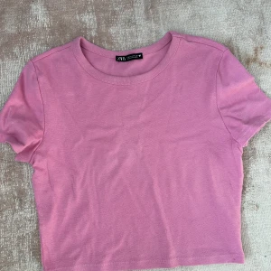 Rosa zara tröja  - Säljer denna rosa lite kortare t-shirten från zara. Köpt sommaren 2021 för ca 100kr. Använd fåtal gånger ny skick.