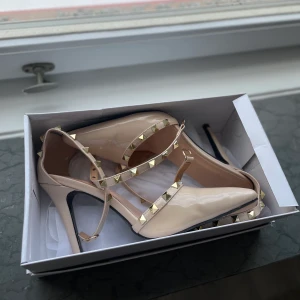 Klackar - Ser ut som valentino klackar. Klackhöjd: 10cm, storlek 40. Skulle säga att dom passar någon med storlek 39/40. Snygg beige färg med band man fäster rund fotleden. Snyggaste skorna, tyvärr kommer dom aldrig till användning. Vet inte vart de kommer ifrån då jag fick dom. Skickar med spårbar frakt genom PostNord. Frakten står köparen för, betalning sker via Swish😊