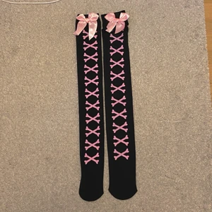 Knästrumpor med rosetter - Knästrumpor med rosett och mönster. Svarta o rosa. Aldrig använt endast testade. Jag tar frakt men behövde fylla i en leveransmetod för Plick har uppdaterats så kan inte välja eget alternativ. Frakt kostar 13kr!