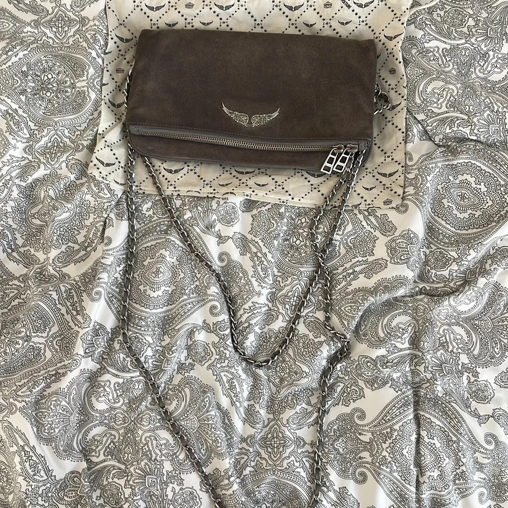 Zadig Voltaire Rock Clutch in gray suede and silver metal details. Bought in 2018 used several times but still in very good condition. Two straps one long and one shorter. 4 different compartments. Comes with dustbag.. Väskor.