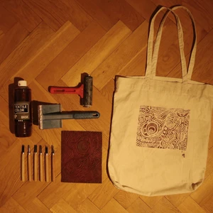 Tygväska med unikt tryck  - Vit tygväska med ett grafiskt tryck jag gjort själv av linoleumplast. På första bilden ser man alla verktyg jag använt i processen. Går att få i olika färger. Handtagen 67cm. Rymmer 10l. 