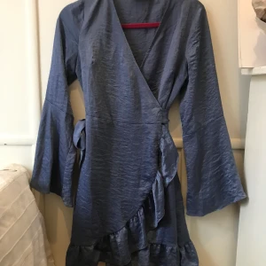 Fest klänning - En klänning i blått glansigt material där man själv kan ändra midjan med ett band. Super fin till olika tillfällen. Tror att den är från nakd.