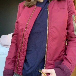 Röd bomberjacka från Schott storlek XS - Röd bomberjacka från märket schott i fint använt skick. Inga hål eller dylikt. Storlek XS och passar perfekt om man brukar ha den storleken. Inköpt runt 2018 men inte använd sen 2 år tillbaka ungefär. Är lite osäker på vikten men kollar såklart upp det vid intresse för plagget för att få exakt fraktkostnad