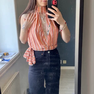 Randig topp - Randig topp i stretchigt tyg och knyt i sidan med öppen rygg. Knappar bak vid nacken. Jag är 166cm lång & bär strl 32/XXS, skulle säga att den blir lite oversize på mig fast den går att strama åt med hjälp av banden i midjan, tror dock den skulle sitta bättre på någon med lite större storlek!