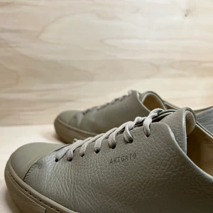 Axel Arigato, Clean 90, beige, strl 42 - Sneakers i modellen Clean 90 från Axel Arigato. Tidlös design med en subtil logotyp i guldton. Skador finns, se mindre förslitningar på båda tåkapporna och en större på vänster häl. Dojorna är välanvända men överlag i ett bra skick. Storlek: 42. Färg: Beige. Nypris: 1950 kr (2019). Skick: Bra. Dustbag: Nej. Kartong: Nej. 100 % läder. Läderfodring. Gummisula.