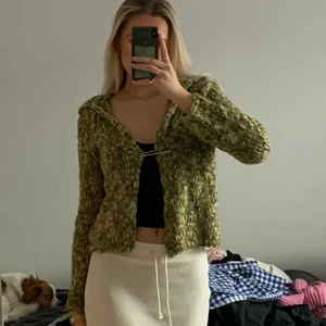 Stickad kofta  - Grön stickad kofta med en stor säkerhetsnål. Står ingen storlek vad jag kan se men skulle gissa på typ S. 