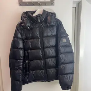 En äldre Moncler Maya men som fortfarande är i väldigt bra skicka förutom att fickan på armen där Moncler loggan sitter inte går att öppna. Detta beror på att när jag la in jackan för säsongen så hade den vikit sig och blivit böjd när jag tog ut den för nästa säsong. Vilket resulterade i att den pekade utåt hela tiden. Så jag applicerade lite lite lim för att den inte skulle sticka ut. En kemtvätt så är den som ny förutom att man inte kan öppna den fickan då. Men man använder aldrig den fickan ä