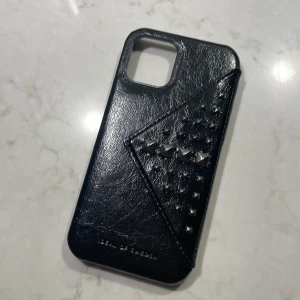 Ideal of Sweden mobilskal (svart) - Svart Ideal of Sweden mobilskal med silvriga metal nitar på och en kortficka (iPhone 12). Används en gång, i skick som ny🤍